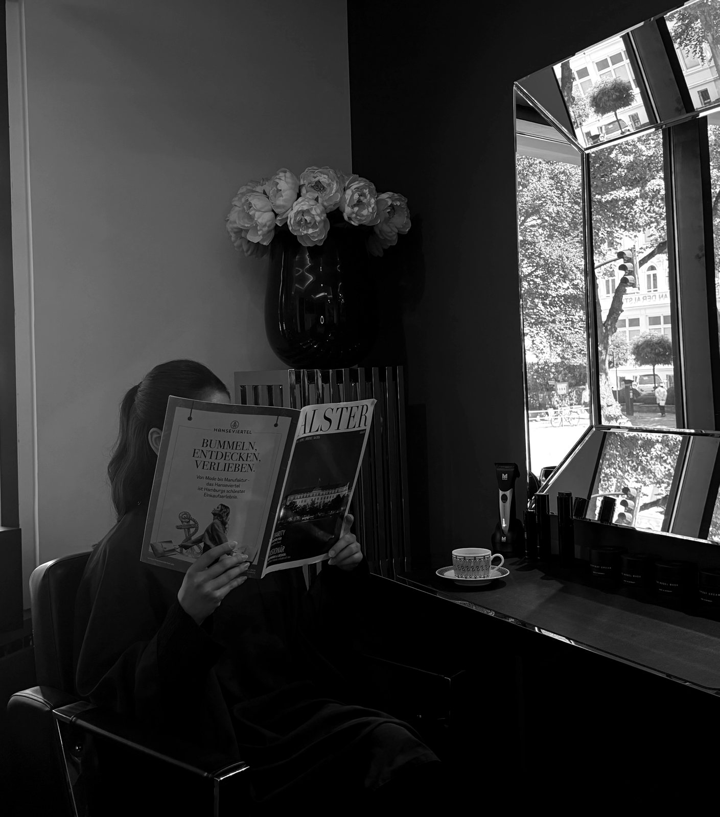 Kundin liest am Styling-Platz, Blick durchs Fenster auf den Mittelweg