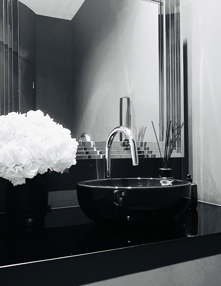 Schwarzes Waschbecken mit Chromarmatur und Hortensien